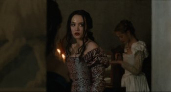 Movie still from “Queen Margot” (1994), directed by Patrice Chéreau – A woman in a dress standing next to a candle; Medium shot, Over the shoulder angle