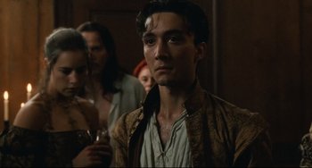 Movie still from “Queen Margot” (1994), directed by Patrice Chéreau – A man in a brown and black jacket standing in front of a group of people; Close Up shot, Over the shoulder angle