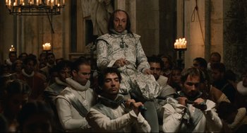 Movie still from “Queen Margot” (1994), directed by Patrice Chéreau – A group of men sitting in a room; Wide shot, Over the shoulder angle
