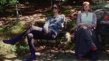 Movie still from “Queen of Earth” (2015), directed by Alex Ross Perry – Two women sitting on a chair in the woods; Medium shot, Over the shoulder angle