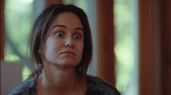 Movie still from “Queen of Earth” (2015), directed by Alex Ross Perry – A person with a surprised look on their face; Close Up shot, Over the shoulder angle