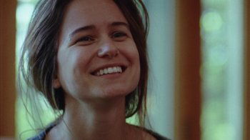 Movie still from “Queen of Earth” (2015), directed by Alex Ross Perry – A person smiling; Close Up shot, Over the shoulder angle
