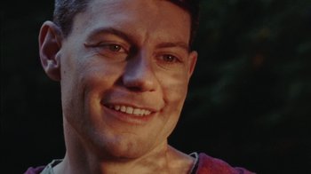 Movie still from “Queen of Earth” (2015), directed by Alex Ross Perry – A man smiling for the camera; Close Up shot, Low angle