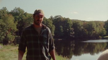 Movie still from “Queen of Earth” (2015), directed by Alex Ross Perry – A man standing in front of a body of water; Medium shot, Low angle