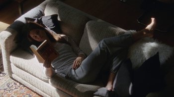 Movie still from “Queen of Earth” (2015), directed by Alex Ross Perry – A woman is laying on a couch reading a book; Wide shot, High angle