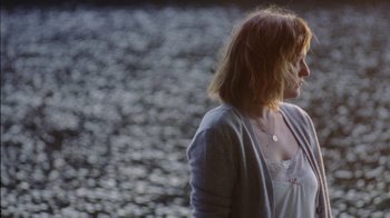 Movie still from “Queen of Earth” (2015), directed by Alex Ross Perry – A woman standing in front of a body of water; Medium shot, Over the shoulder angle