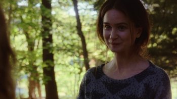 Movie still from “Queen of Earth” (2015), directed by Alex Ross Perry – A woman standing in front of a forest; Close Up shot, Over the shoulder angle