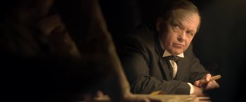 Movie still from “Queen of the Desert” (2015), directed by Werner Herzog – A man sitting at a table in a dark room looking at a laptop computer; Close Up shot, Over the shoulder angle