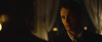 Movie still from “Queen of the Desert” (2015), directed by Werner Herzog – A person wearing a suit and tie; Close Up shot, Over the shoulder angle