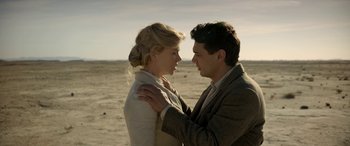 Movie still from “Queen of the Desert” (2015), directed by Werner Herzog – A man and a woman standing next to each other on a beach; Medium shot, Low angle