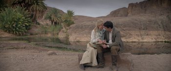 Movie still from “Queen of the Desert” (2015), directed by Werner Herzog – A man and a woman sitting next to each other on top of a rock; Wide shot, High angle