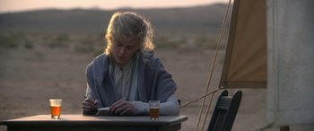Movie still from “Queen of the Desert” (2015), directed by Werner Herzog – A woman sitting at a table writing on a book; Medium shot, Over the shoulder angle