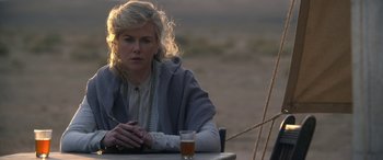 Movie still from “Queen of the Desert” (2015), directed by Werner Herzog – A woman sitting at a table in front of a glass of beer; Close Up shot, Over the shoulder angle