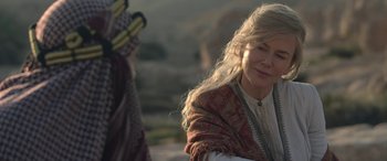 Movie still from “Queen of the Desert” (2015), directed by Werner Herzog – A woman with long blonde hair wearing a red shawl; Close Up shot, Over the shoulder angle