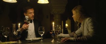 Movie still from “Queen of the Desert” (2015), directed by Werner Herzog – A man and a woman sitting at a dinner table; Medium shot, Low angle