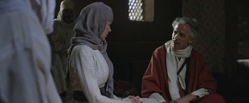 Movie still from “Queen of the Desert” (2015), directed by Werner Herzog – A woman wearing a headscarf talking to an older man; Medium shot, Over the shoulder angle
