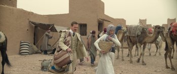 Movie still from “Queen of the Desert” (2015), directed by Werner Herzog – A group of people walking down a dirt road; Wide shot, Over the shoulder angle