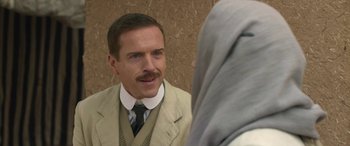 Movie still from “Queen of the Desert” (2015), directed by Werner Herzog – A man in a suit and tie looking into a mirror; Close Up shot, Over the shoulder angle