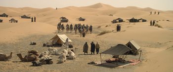 Movie still from “Queen of the Desert” (2015), directed by Werner Herzog – A group of people riding horses in the desert; Extreme Wide shot, High angle