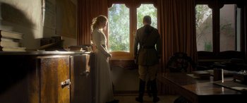 Movie still from “Queen of the Desert” (2015), directed by Werner Herzog – A man and a woman standing in front of a window; Wide shot, Low angle