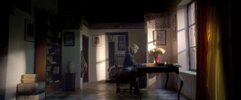 Movie still from “Queen of the Desert” (2015), directed by Werner Herzog – A woman sitting at a table in a living room; Wide shot, Low angle