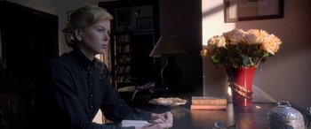 Movie still from “Queen of the Desert” (2015), directed by Werner Herzog – A woman sitting at a table in front of a lamp; Medium shot, Over the shoulder angle