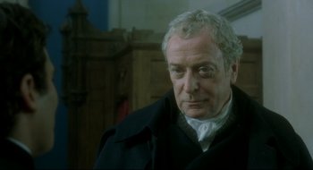 Movie still from “Quills” (2000), directed by Philip Kaufman – An older man wearing a black coat and a white shirt; Close Up shot, Over the shoulder angle