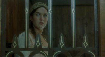 Movie still from “Quills” (2000), directed by Philip Kaufman – A young woman looking through a fence at a building; Close Up shot, Low angle