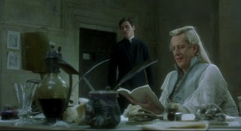 Movie still from “Quills” (2000), directed by Philip Kaufman – Two people sitting at a dinner table reading books; Medium shot, Over the shoulder angle