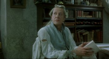 Movie still from “Quills” (2000), directed by Philip Kaufman – An older man wearing a white shirt and a white wig; Medium shot, Over the shoulder angle