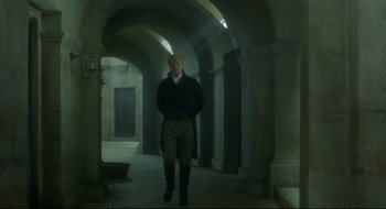 Movie still from “Quills” (2000), directed by Philip Kaufman – A man standing in an archway in a building; Wide shot, Low angle