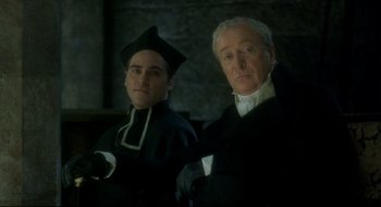 Movie still from “Quills” (2000), directed by Philip Kaufman – Two men dressed in black and white standing next to each other; Medium shot, Low angle