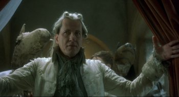 Movie still from “Quills” (2000), directed by Philip Kaufman – A man in a white jacket and some other people in the background; Close Up shot, Low angle