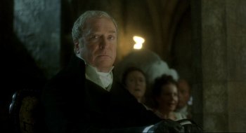 Movie still from “Quills” (2000), directed by Philip Kaufman – A man sitting in front of a group of people; Close Up shot, Low angle