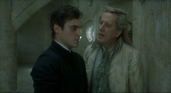 Movie still from “Quills” (2000), directed by Philip Kaufman – A man standing next to another man in a room; Medium shot, Over the shoulder angle