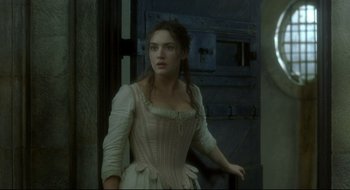Movie still from “Quills” (2000), directed by Philip Kaufman – A woman in a white dress standing in front of a blue door; Medium shot, Over the shoulder angle