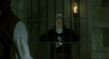 Movie still from “Quills” (2000), directed by Philip Kaufman – An old man standing behind bars in a jail cell; Medium shot, Over the shoulder angle