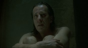 Movie still from “Quills” (2000), directed by Philip Kaufman – A man sitting in a dark room with his arms crossed; Close Up shot, Low angle