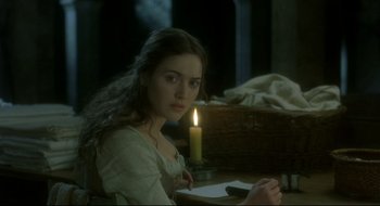 Movie still from “Quills” (2000), directed by Philip Kaufman – A woman sitting in front of a lit candle in a room; Medium shot, Over the shoulder angle