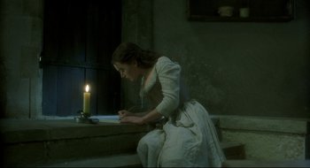 Movie still from “Quills” (2000), directed by Philip Kaufman – A woman writing on a piece of paper next to a lit candle; Medium shot, High angle