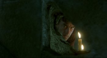 Movie still from “Quills” (2000), directed by Philip Kaufman – A man looking through a hole in the wall at a candle; Close Up shot, Low angle