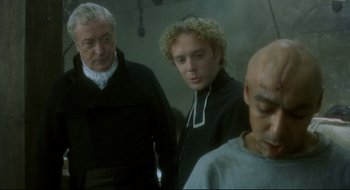 Movie still from “Quills” (2000), directed by Philip Kaufman – Two men and a woman standing next to each other in a room; Medium shot, Over the shoulder angle