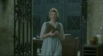 Movie still from “Quills” (2000), directed by Philip Kaufman – A woman standing in a room holding a book in her hands; Medium shot, Low angle