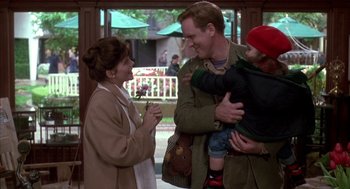 Movie still from “Raising Cain” (1992), directed by Brian De Palma – A man and a woman holding a child and smiling; Medium shot, Over the shoulder angle