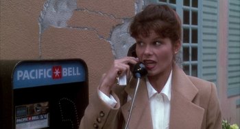 Movie still from “Raising Cain” (1992), directed by Brian De Palma – A woman talking on a phone next to a parking meter; Close Up shot, High angle