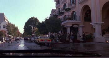 Movie still from “Raising Cain” (1992), directed by Brian De Palma – A group of people standing on the side of the street; Wide shot, Low angle