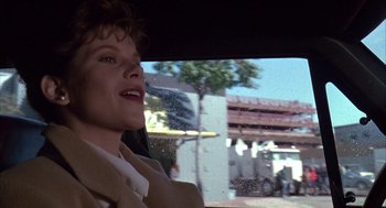 Movie still from “Raising Cain” (1992), directed by Brian De Palma – A woman driving a car on a city street; Close Up shot, Low angle