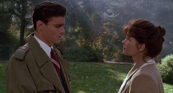 Movie still from “Raising Cain” (1992), directed by Brian De Palma – A man and a woman standing next to each other in a field; Medium shot, Over the shoulder angle