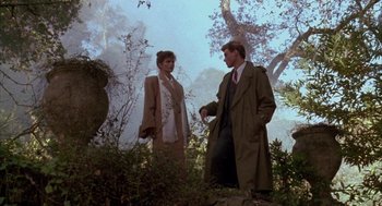 Movie still from “Raising Cain” (1992), directed by Brian De Palma – A man and a woman standing next to each other in the woods; Wide shot, Low angle