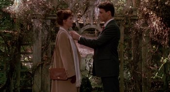 Movie still from “Raising Cain” (1992), directed by Brian De Palma – A man putting a tie on a woman's collar; Medium shot, Over the shoulder angle